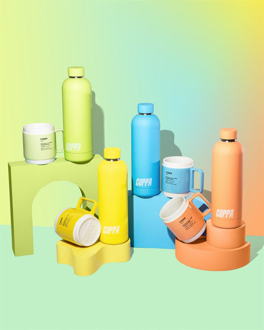 Cuppa mugs and cuppa insulated water bottles in orange yellow blue green on a mutli coloured background with rainbow effect in portrait