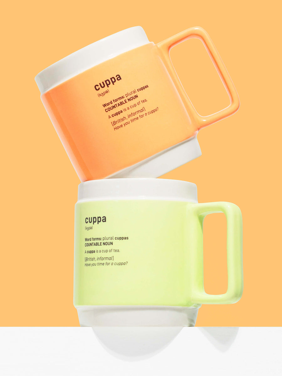 Cuppa 350ml large tea or coffee mugs on an orange background. The terracotta orange mugs is at the top and balanced on the top of the pastel green cuppa mug. Both mugs have rectangular handles that sit comfortable in the hand.