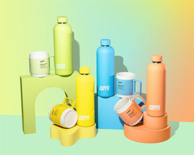 Cuppa mugs and cuppa insulated water bottles in orange yellow blue green on a mutli coloured background with rainbow effect in landscape